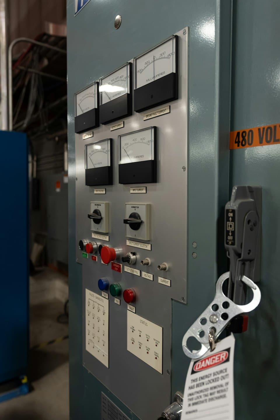 Endüstriyel elektrik panosu, göstergeler, anahtarlar ve uyarı bandı ile.