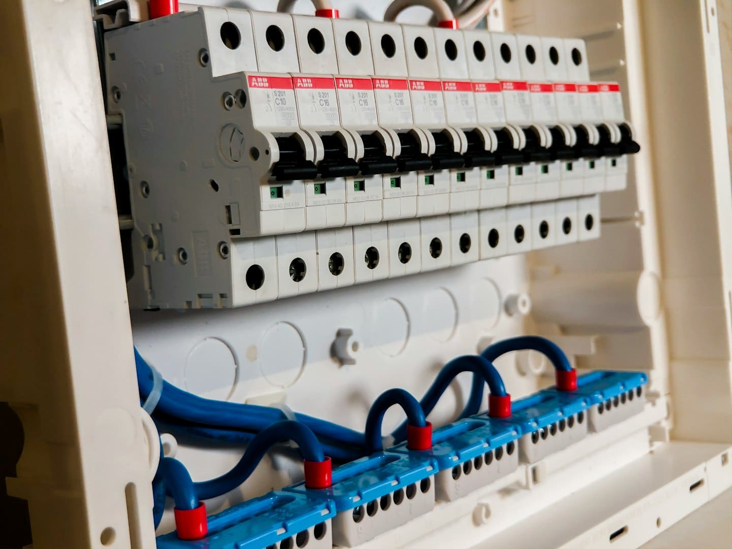 Devre kesiciler ve mavi kablolarla dolu bir elektrik dağıtım panosu.
